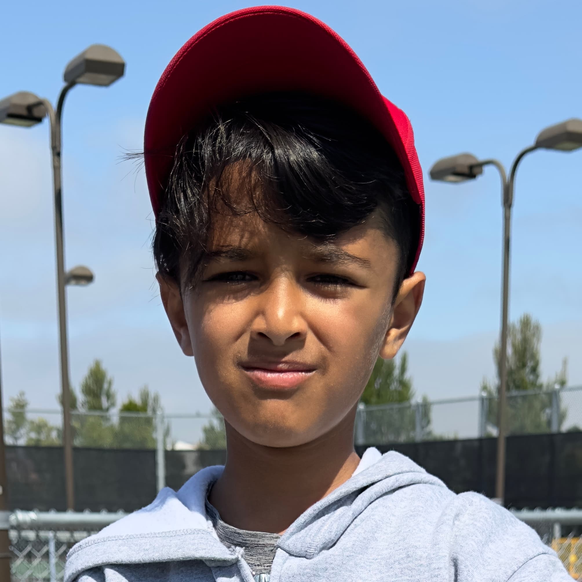 A junior player in a red cap gives a warm, confident portrait smile.