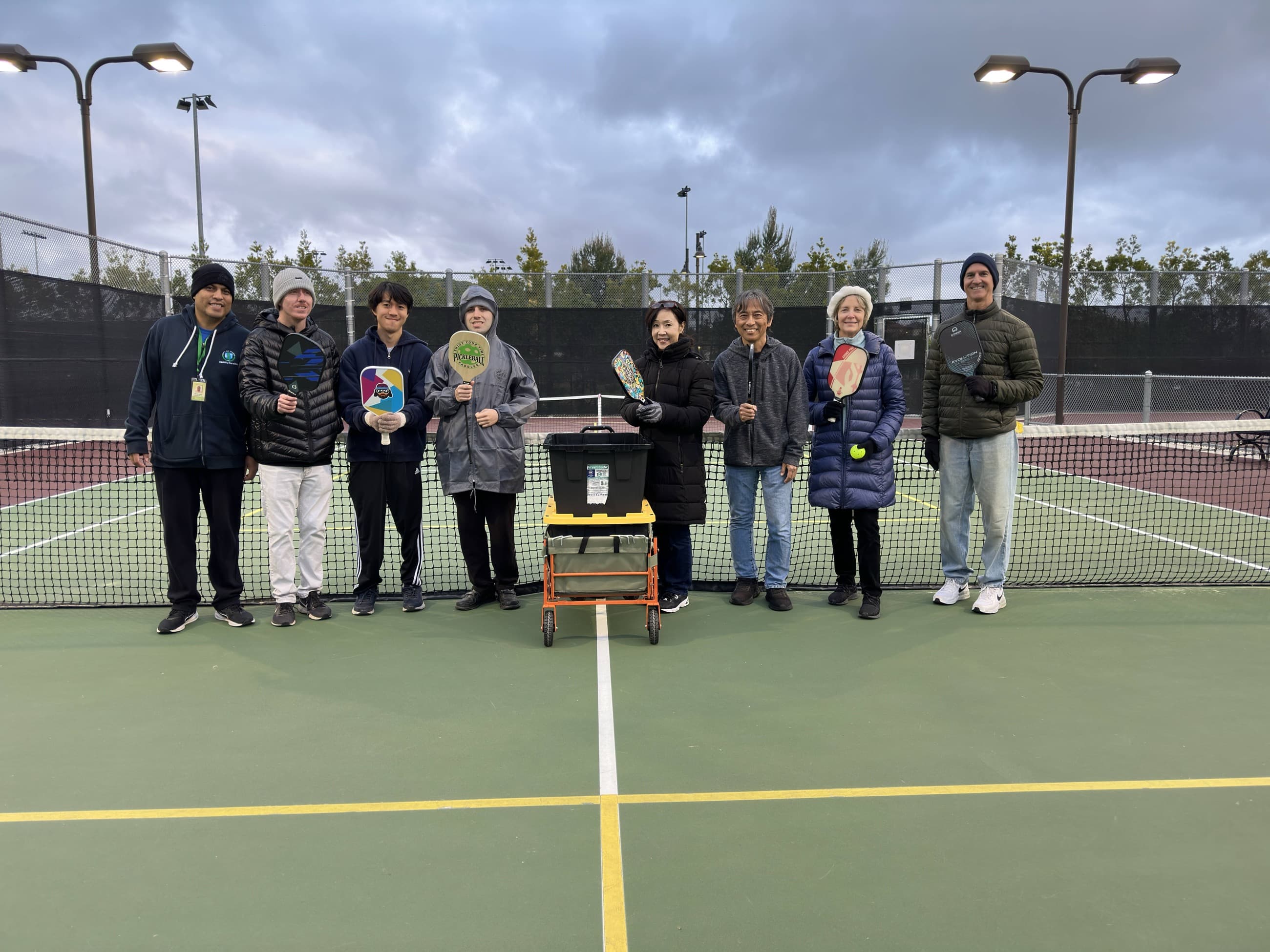 A team gathers around their trophy for a group photo on court.